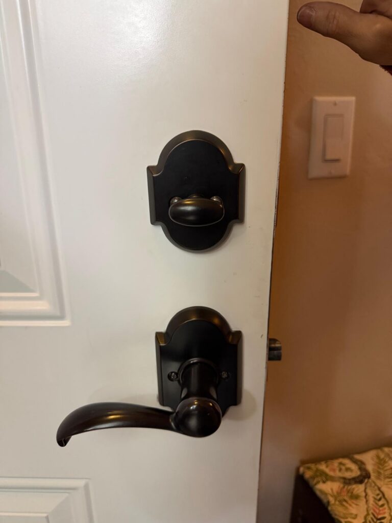 Interior side of a home entry door with a newly installed black deadbolt thumbturn and lever in Edmond, OK