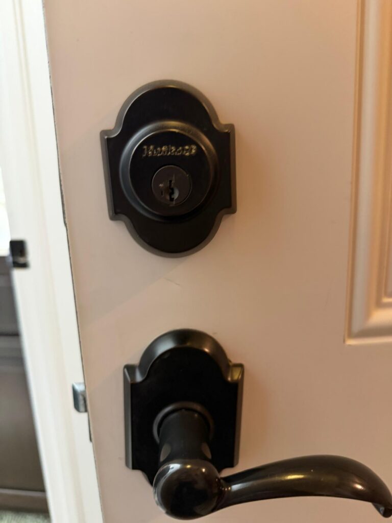 Matte black Kwikset deadbolt and matching lever on a white front door in Edmond, OK
