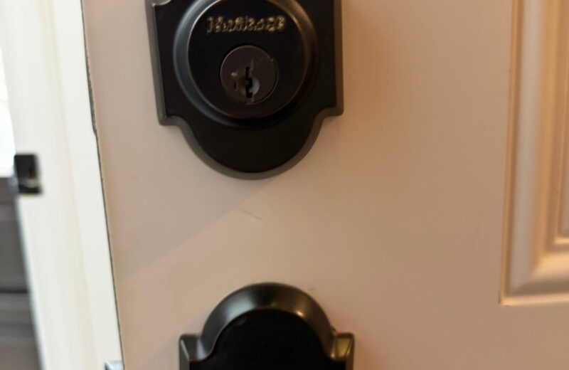 Matte black Kwikset deadbolt and matching lever on a white front door in Edmond, OK