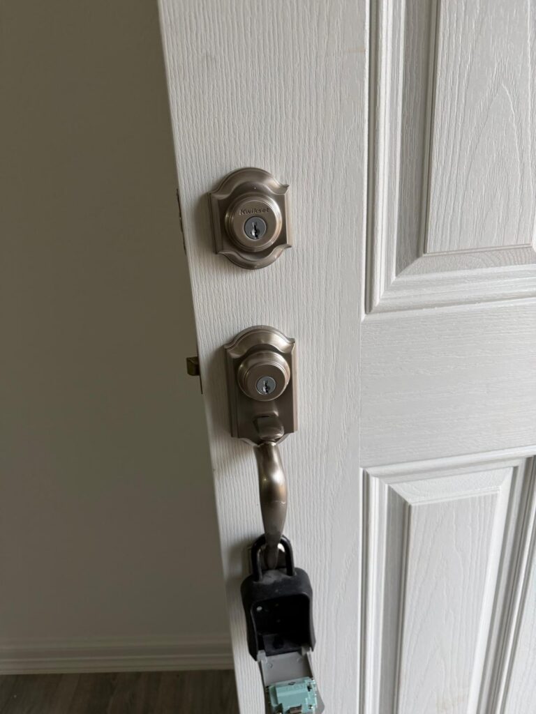 Satin nickel Kwikset deadbolt and handleset with a realtor lockbox on the front door of a home being rekeyed after a sale in Edmond, OK