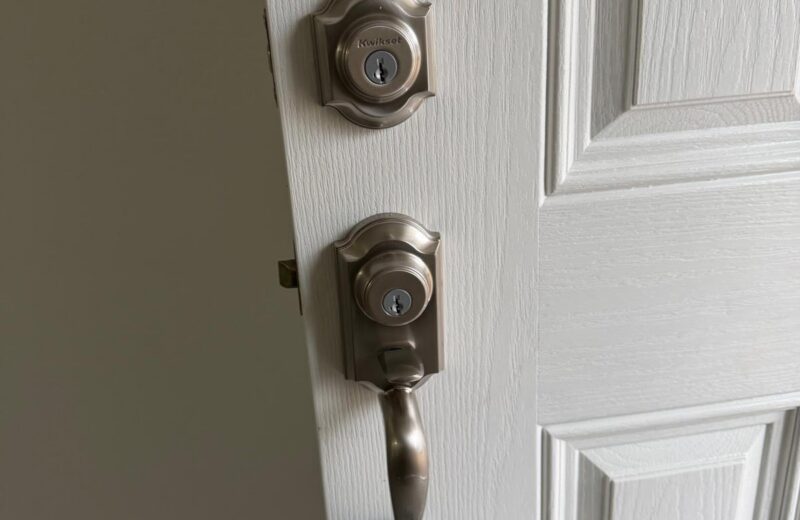 Satin nickel Kwikset deadbolt and handleset with a realtor lockbox on the front door of a home being rekeyed after a sale in Edmond, OK