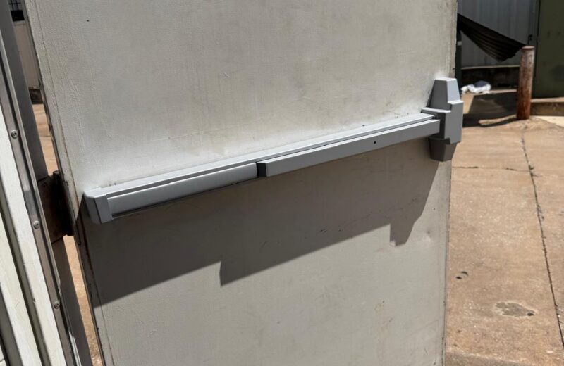 Grey commercial panic bar exit device installed on a steel back door in Oklahoma City