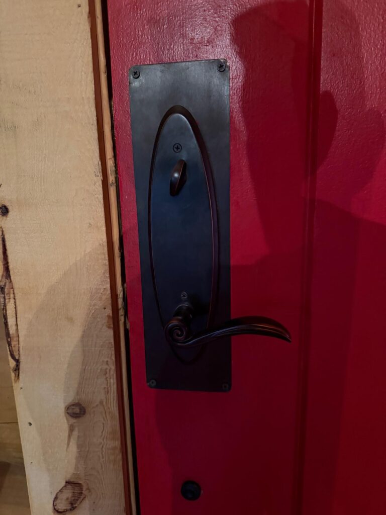 Interior side of a red entry door with an oil-rubbed bronze handleset, lever and deadbolt thumbturn