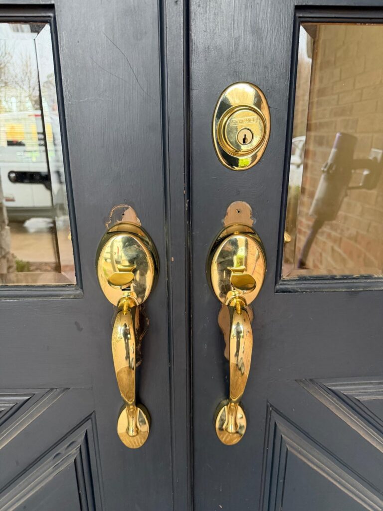 Polished brass Schlage handlesets and deadbolt on black double front doors of a home in Edmond, OK
